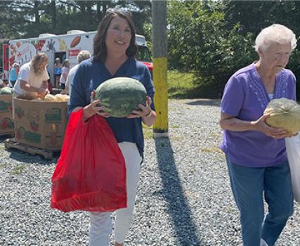 Kim Nechay, executive director of the Perdue Foundation, helps a carry a client&rsquo;s groceries after shopping on the Maryland Food Bank&rsquo;s Mobile Market during a distribution of roughly 2,500 pounds of fresh produce and Perdue-donated chicken in Deal Island, Maryland on Wednesday.