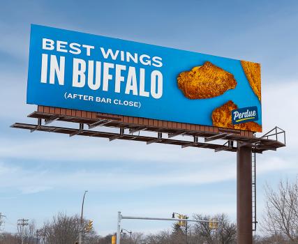 Billboard with a blue background advertising Perdue chicken wings, reading &lsquo;Best Wings in Buffalo.&rsquo; Two wings are shown on the right.
