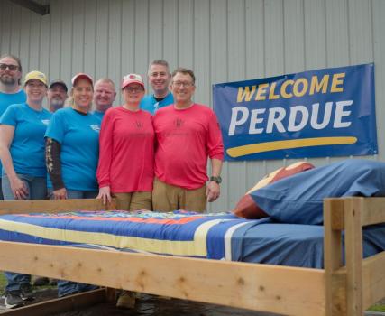 A group holding tools to build a bed as part of Perdue's charity initiatives.