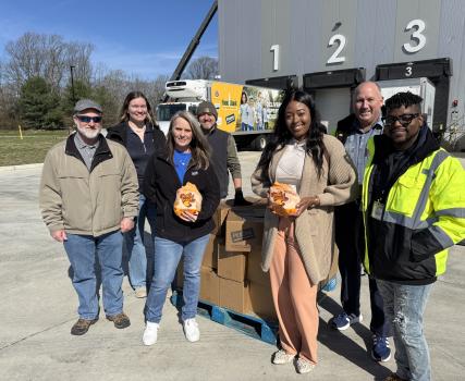 Group of people standing in front of yellow helicopter on tarmac with numbers 1, 2, 3 visible above.