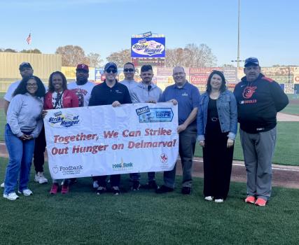 A group of people involved in the Perdue Strike Out Hunger 2026 campaign, holding a banner that says "Together, We Can Strike out Hunger on Delmarva!"