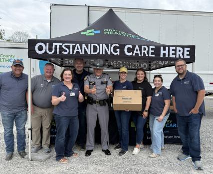 Group of employees posing together in front of a Perdue facility with "Outstanding Care Here" sign.