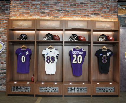 Four Perdue-branded sports jerseys displayed in illuminated cases against a brick wall.