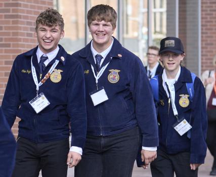 Students in school uniforms and medals walking in school hallway.