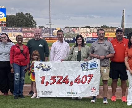 Group of people holding large check for 1,524,407 at outdoor event