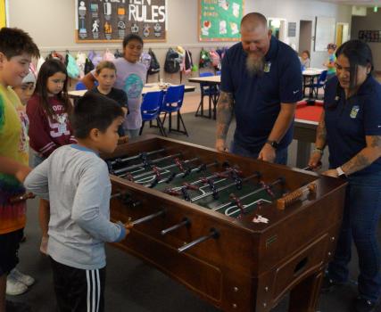 Group of people playing foosball in a recreational facility with colorful striped wall decoration.