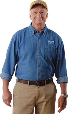 Man wearing blue work shirt and tan pants standing against white background.