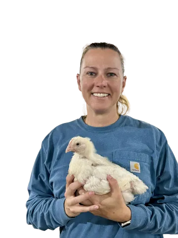Person in blue shirt holding a raw chicken against white background.