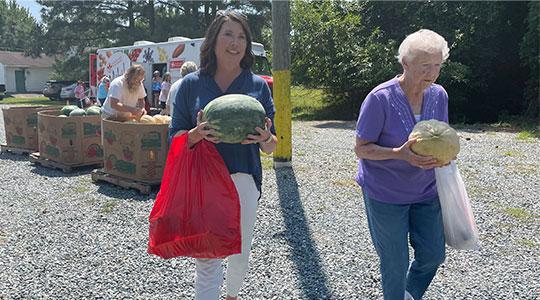 Kim Nechay, executive director of the Perdue Foundation, helps a carry a client&rsquo;s groceries after shopping on the Maryland Food Bank&rsquo;s Mobile Market during a distribution of roughly 2,500 pounds of fresh produce and Perdue-donated chicken in Deal Island, Maryland on Wednesday.