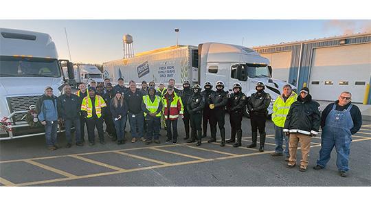 Group of workers in safety vests standing outside a Perdue facility building.