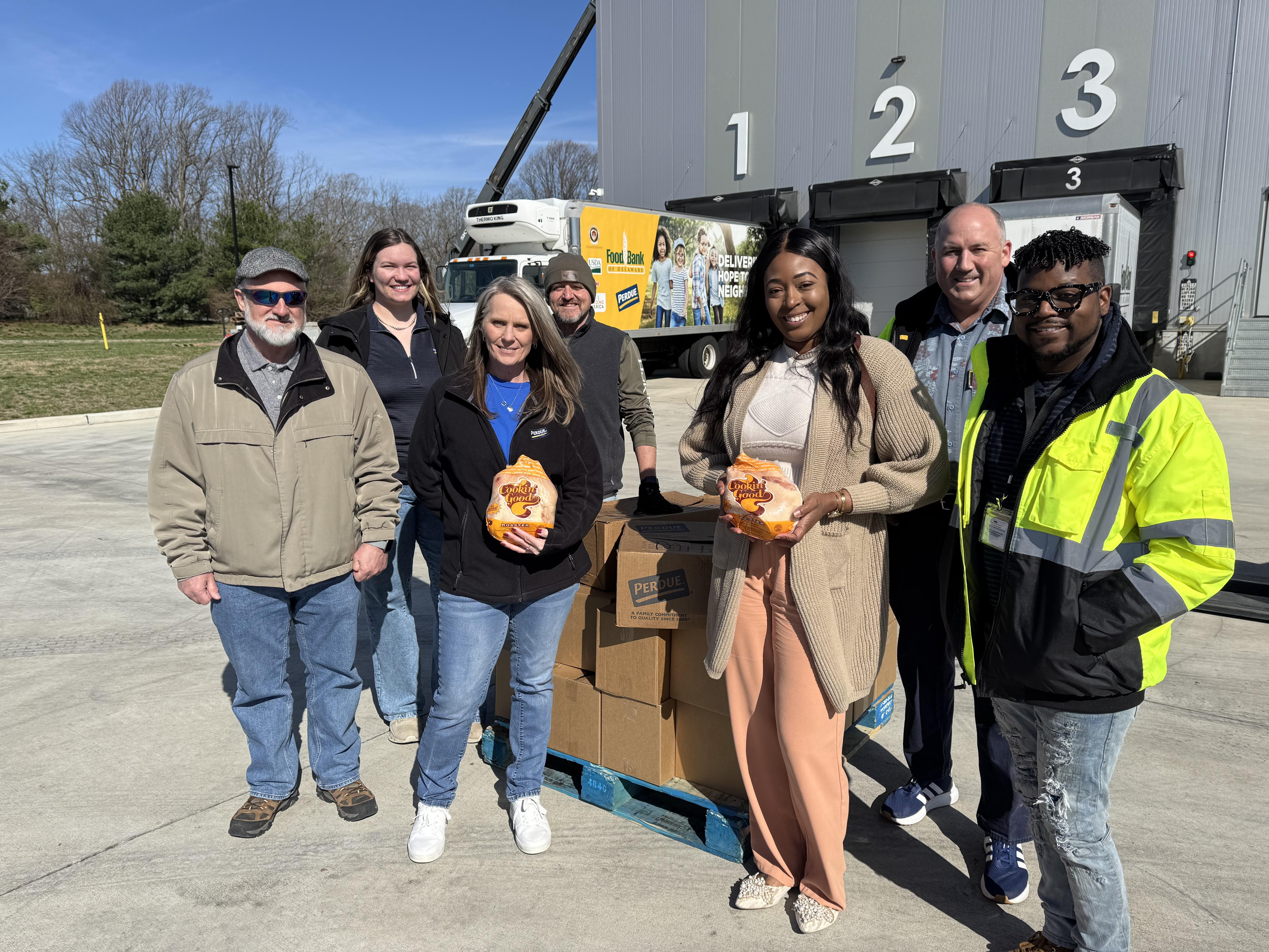 Group of people standing in front of yellow helicopter on tarmac with numbers 1, 2, 3 visible above.