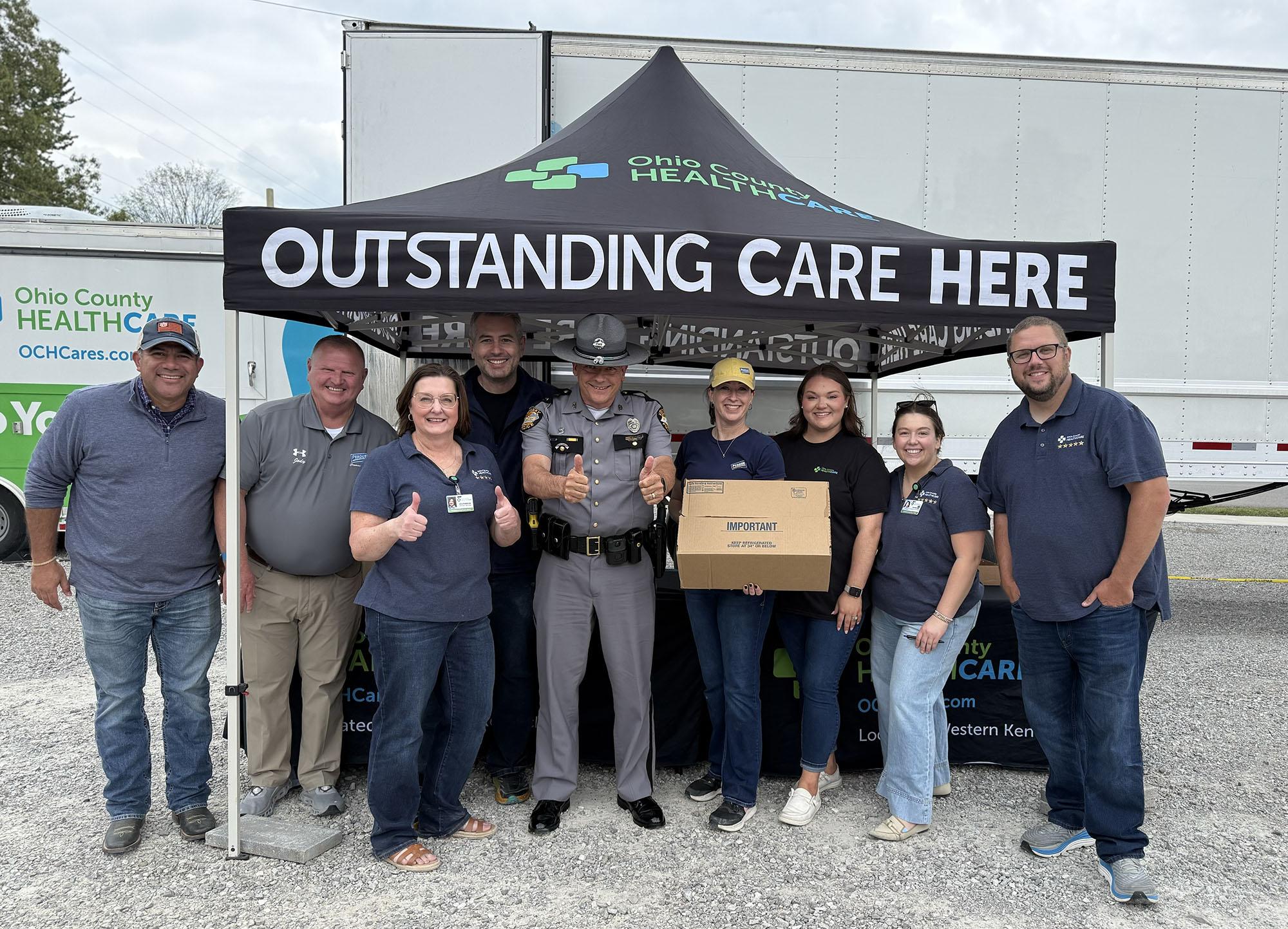 Group of employees posing together in front of a Perdue facility with "Outstanding Care Here" sign.