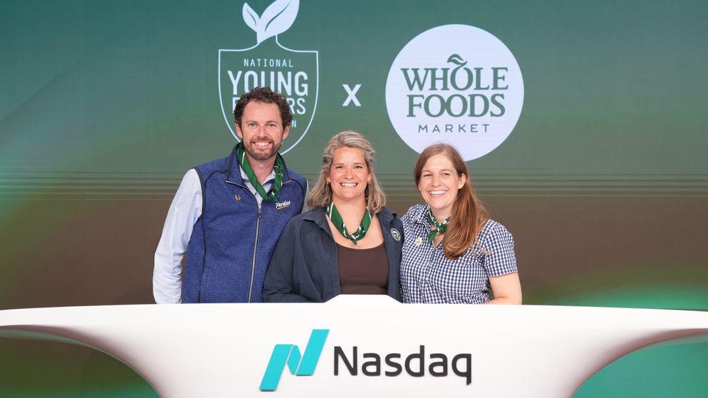 Three people standing at Nasdaq podium with Whole Foods and company logos behind them.