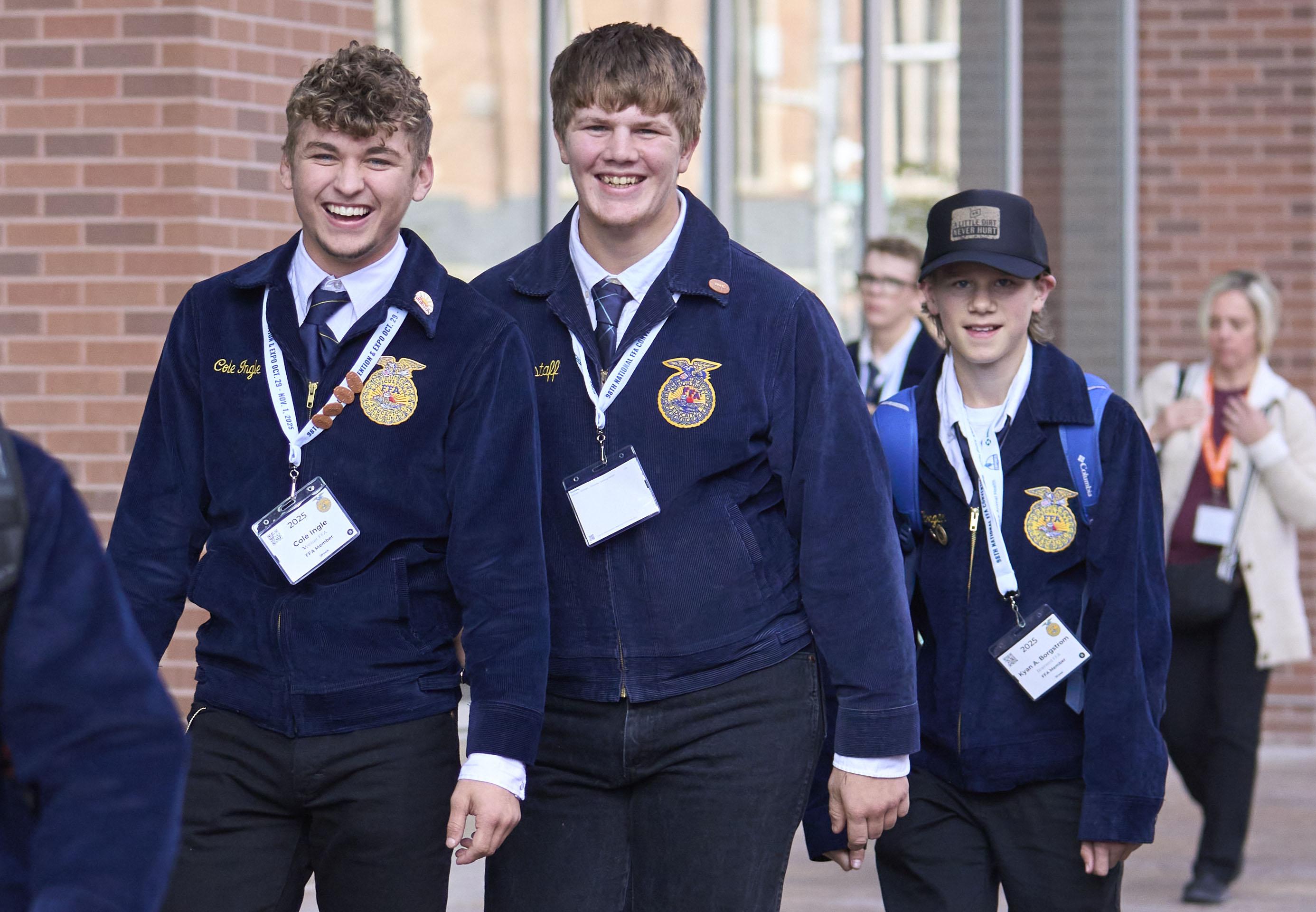 Students in school uniforms and medals walking in school hallway.